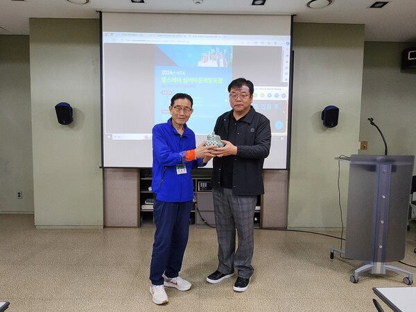 [사진: 건국대학교 도시정비과정 김덕기주임교수가 최고령 원우에게 건강과 장수를 기원하는 백자를 수여하고 있다.@한국도시환경헤럴드]
